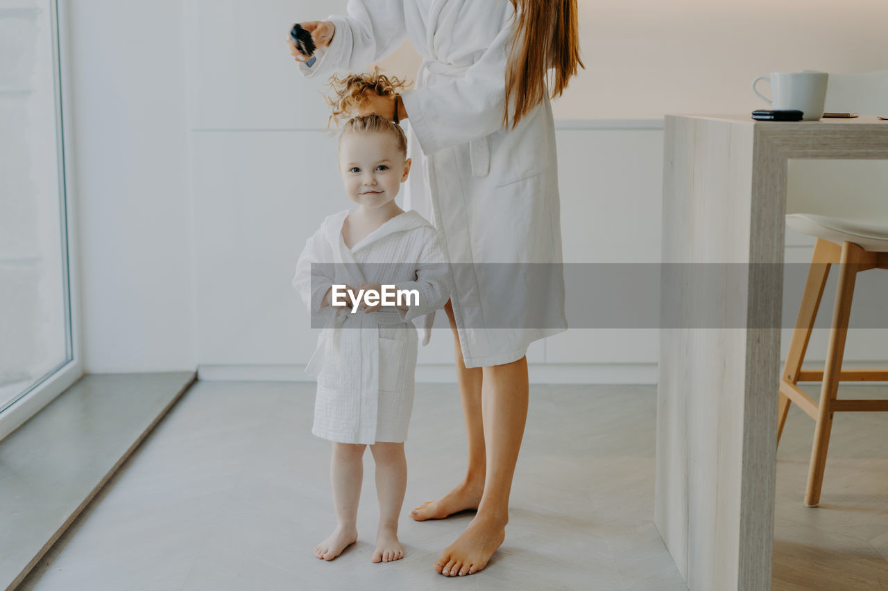 Mother combing daughters hair at home