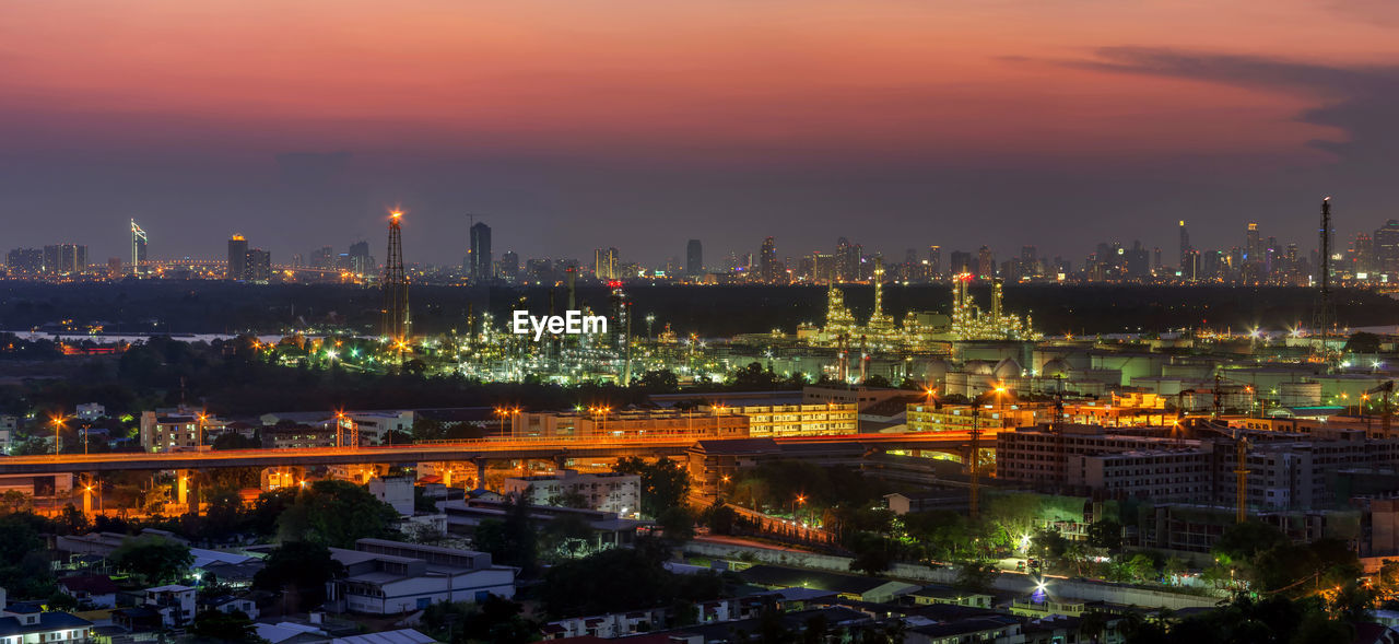 High angle view of illuminated buildings against sky at sunset oil refinery