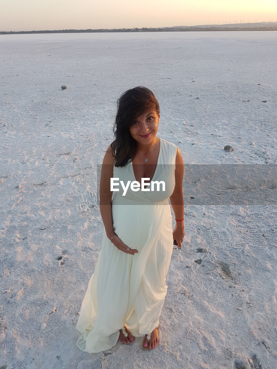 Portrait of pregnant woman standing at beach