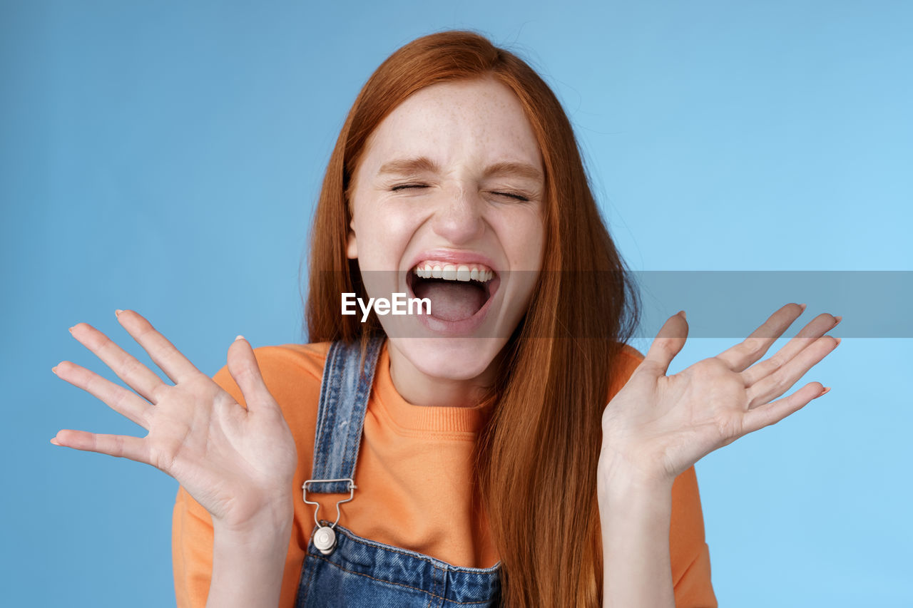 Cheerful woman screaming against blue background