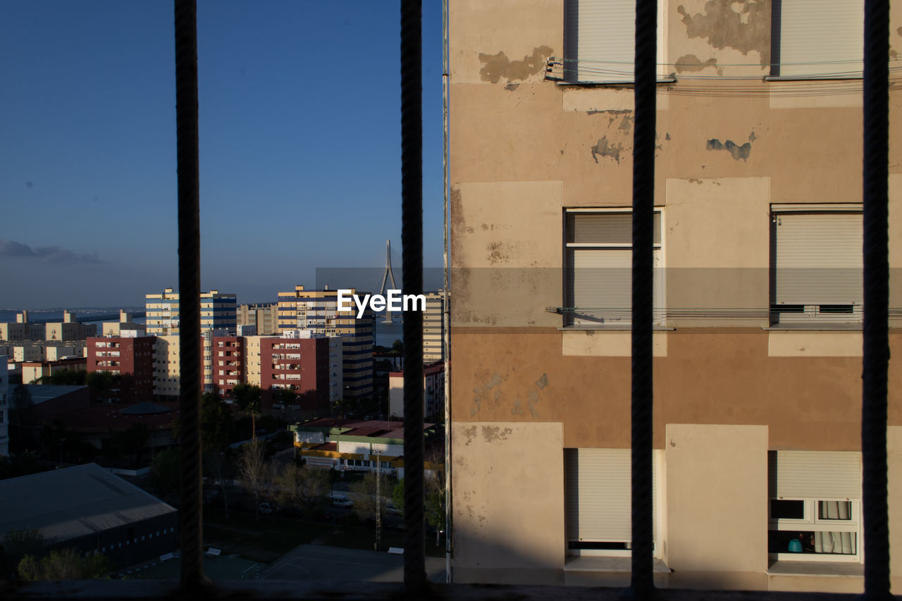 BUILDINGS AGAINST SKY SEEN THROUGH WINDOW