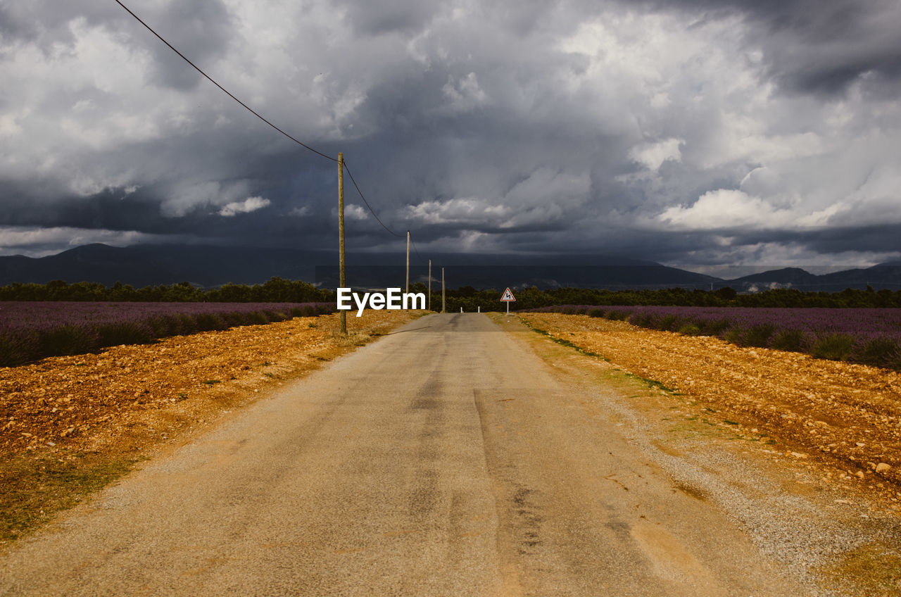 ROAD LEADING TOWARDS AGRICULTURAL FIELD AGAINST SKY