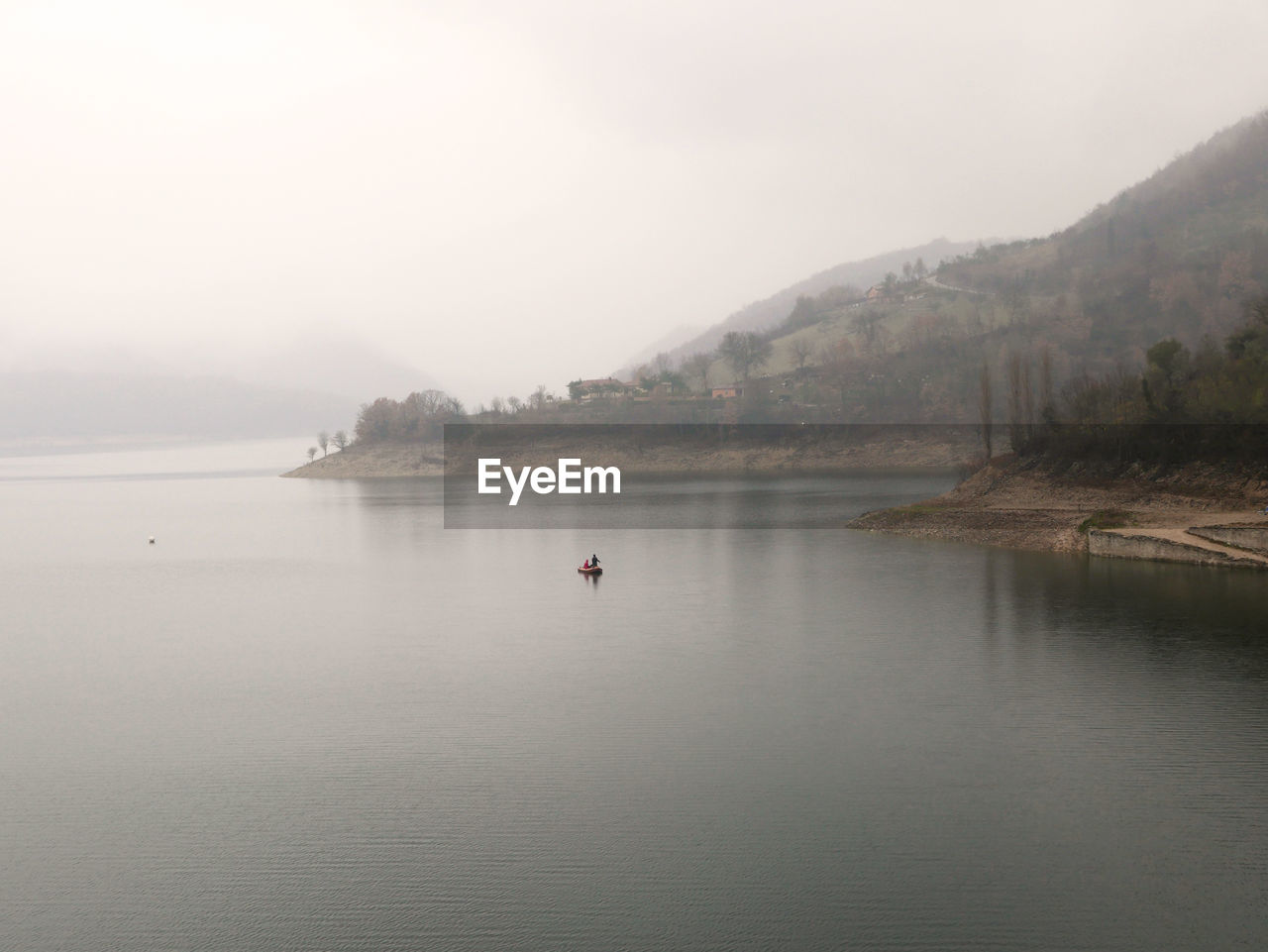 SCENIC VIEW OF LAKE IN FOGGY WEATHER AGAINST SKY