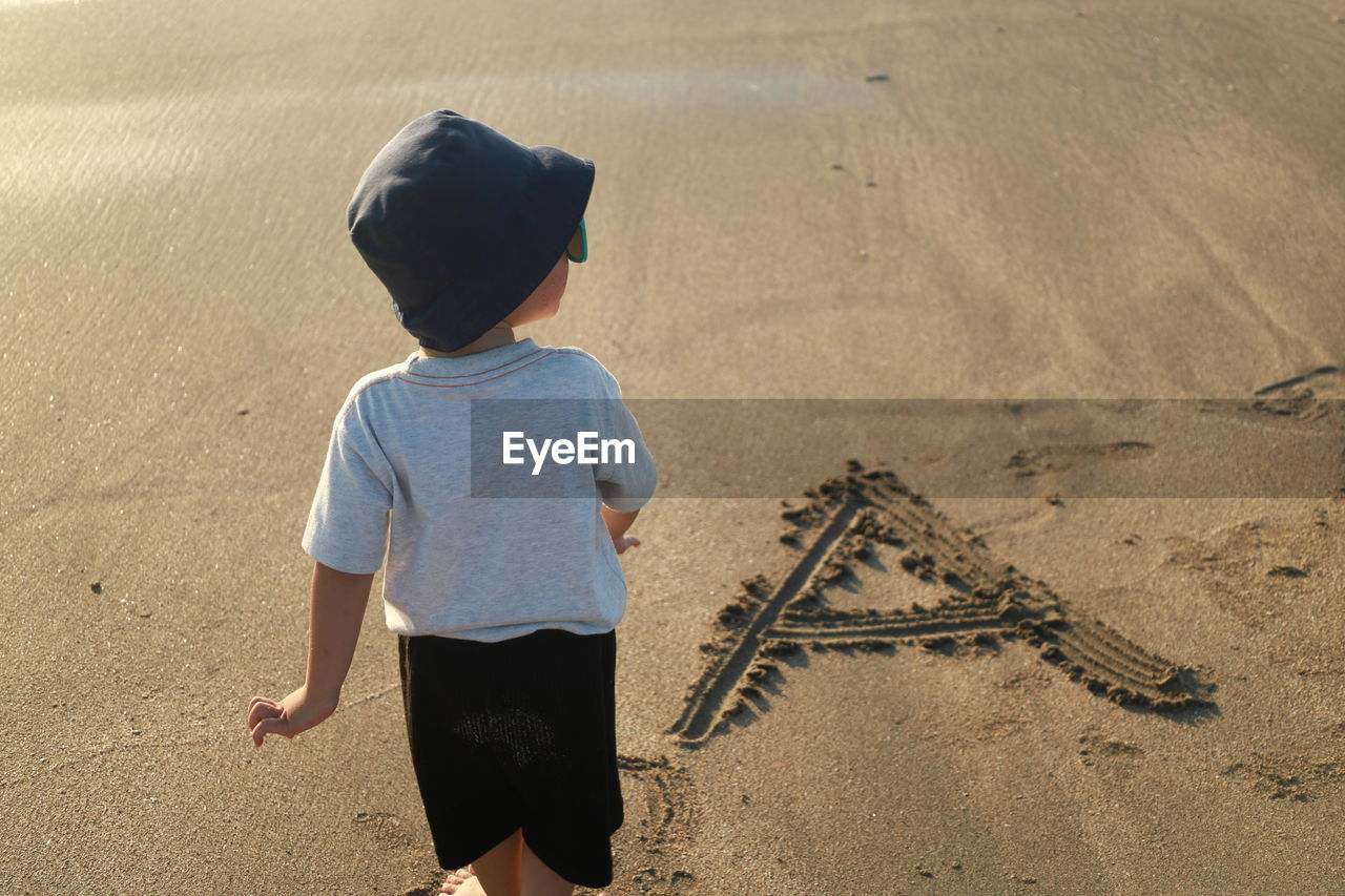 Boy with letter a written in the sand