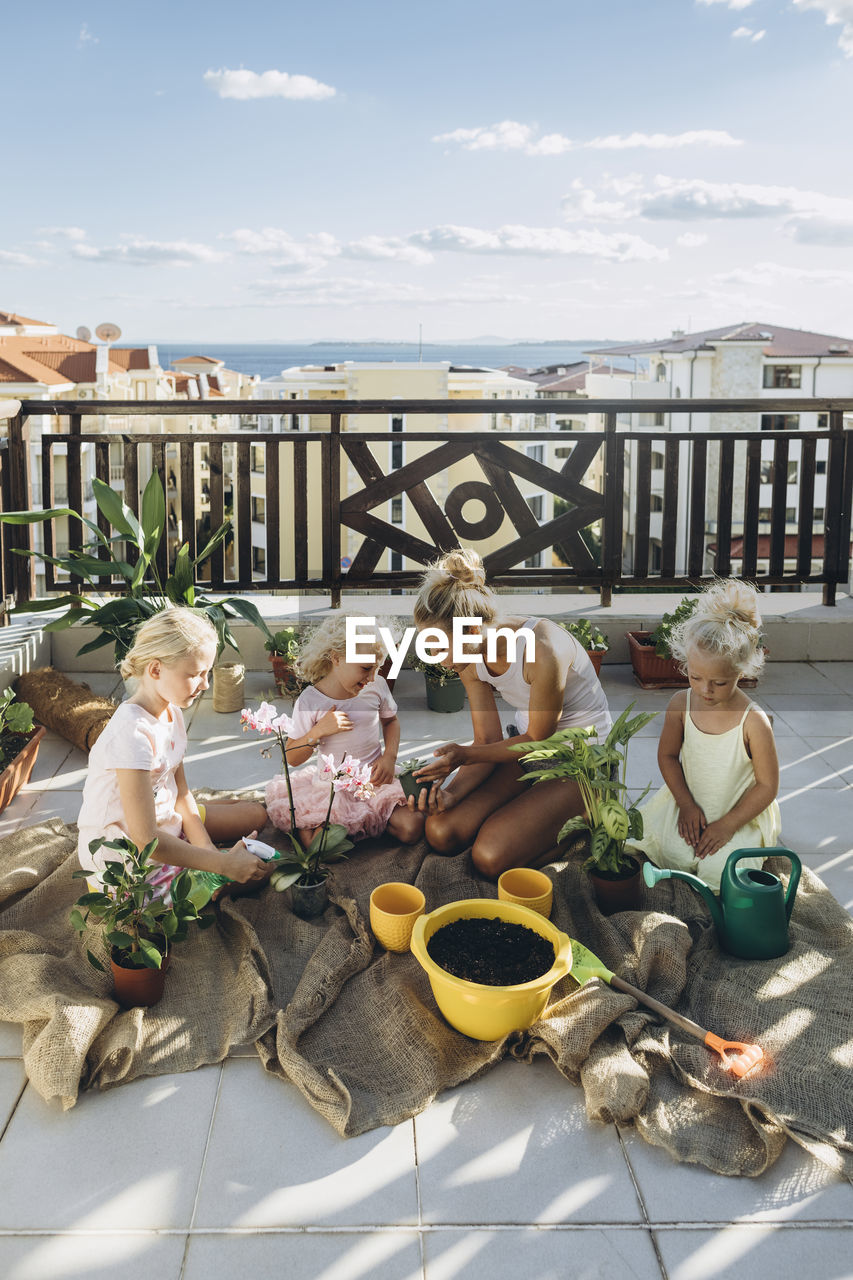 Mother and daughters planting flowers on roof terrace together