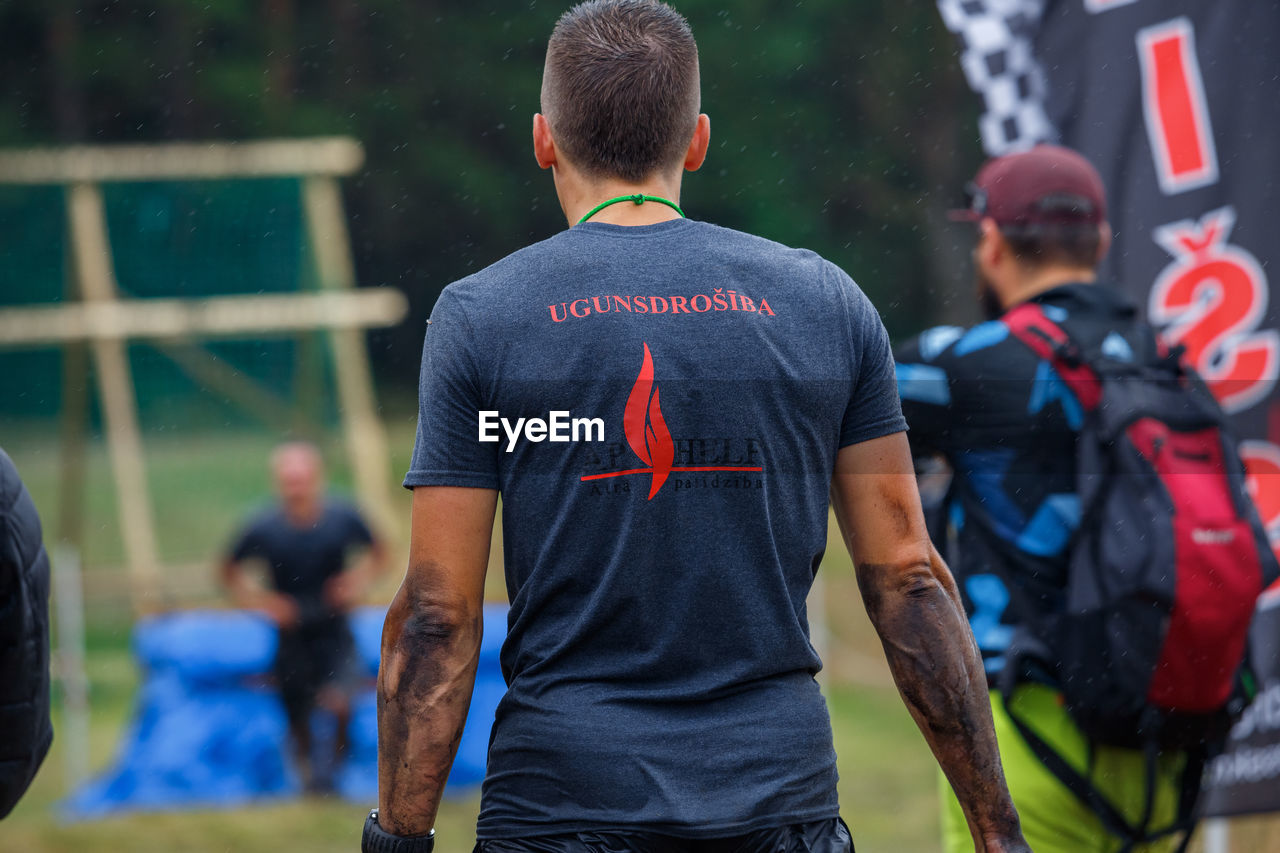 REAR VIEW OF TWO PEOPLE STANDING ON SOCCER FIELD