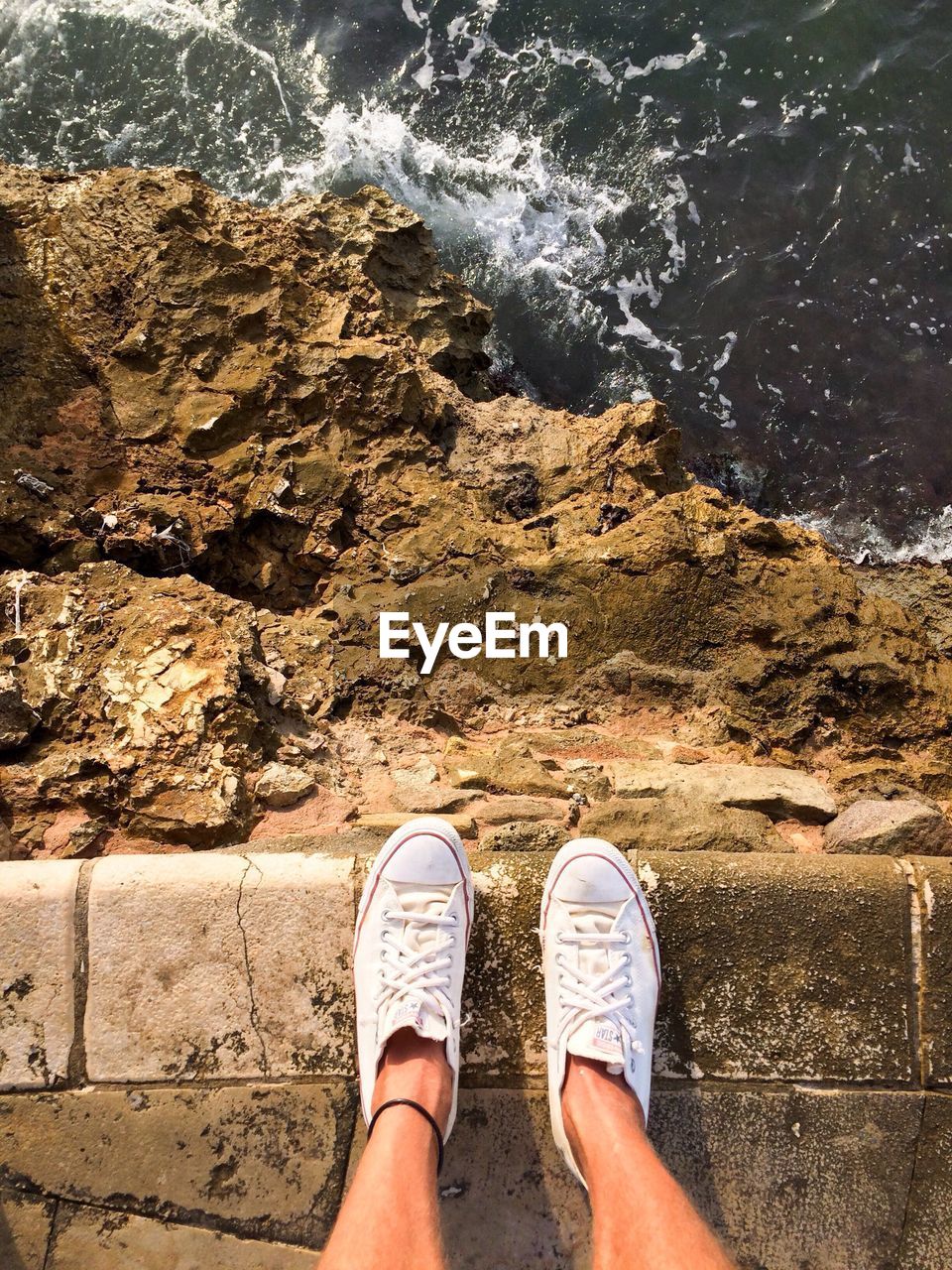 Low section of person standing on pier by sea