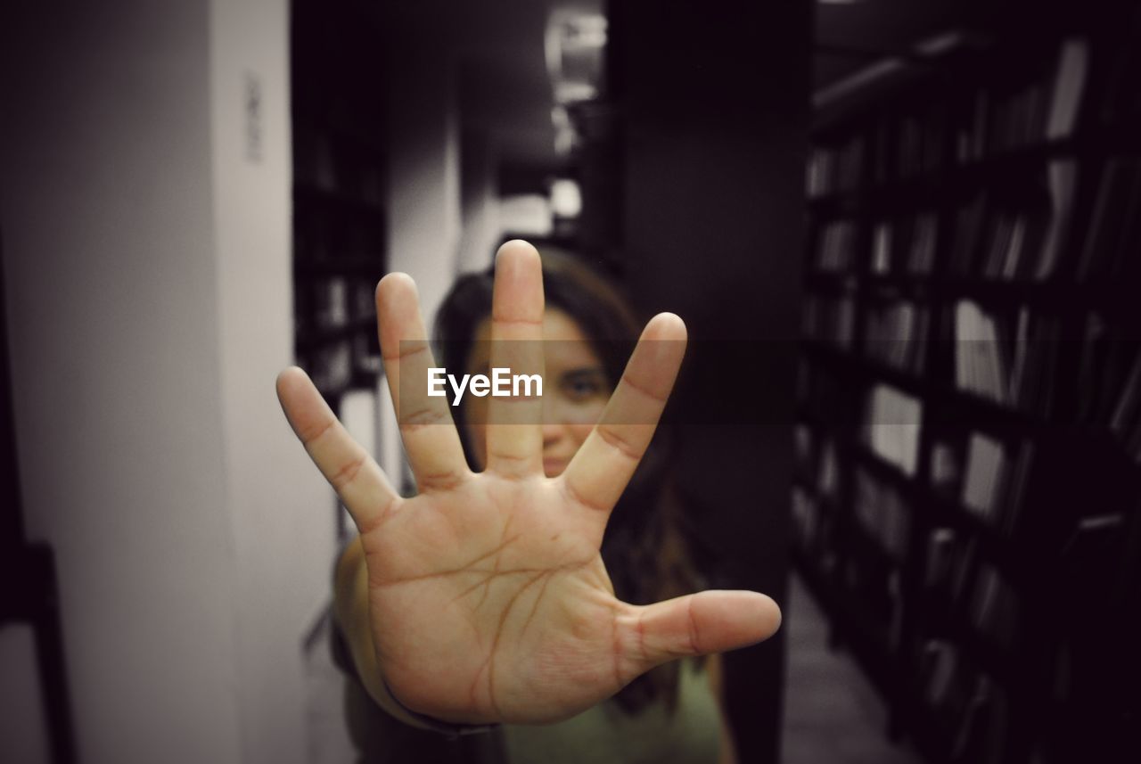 Close-up of woman showing stop gesture in library