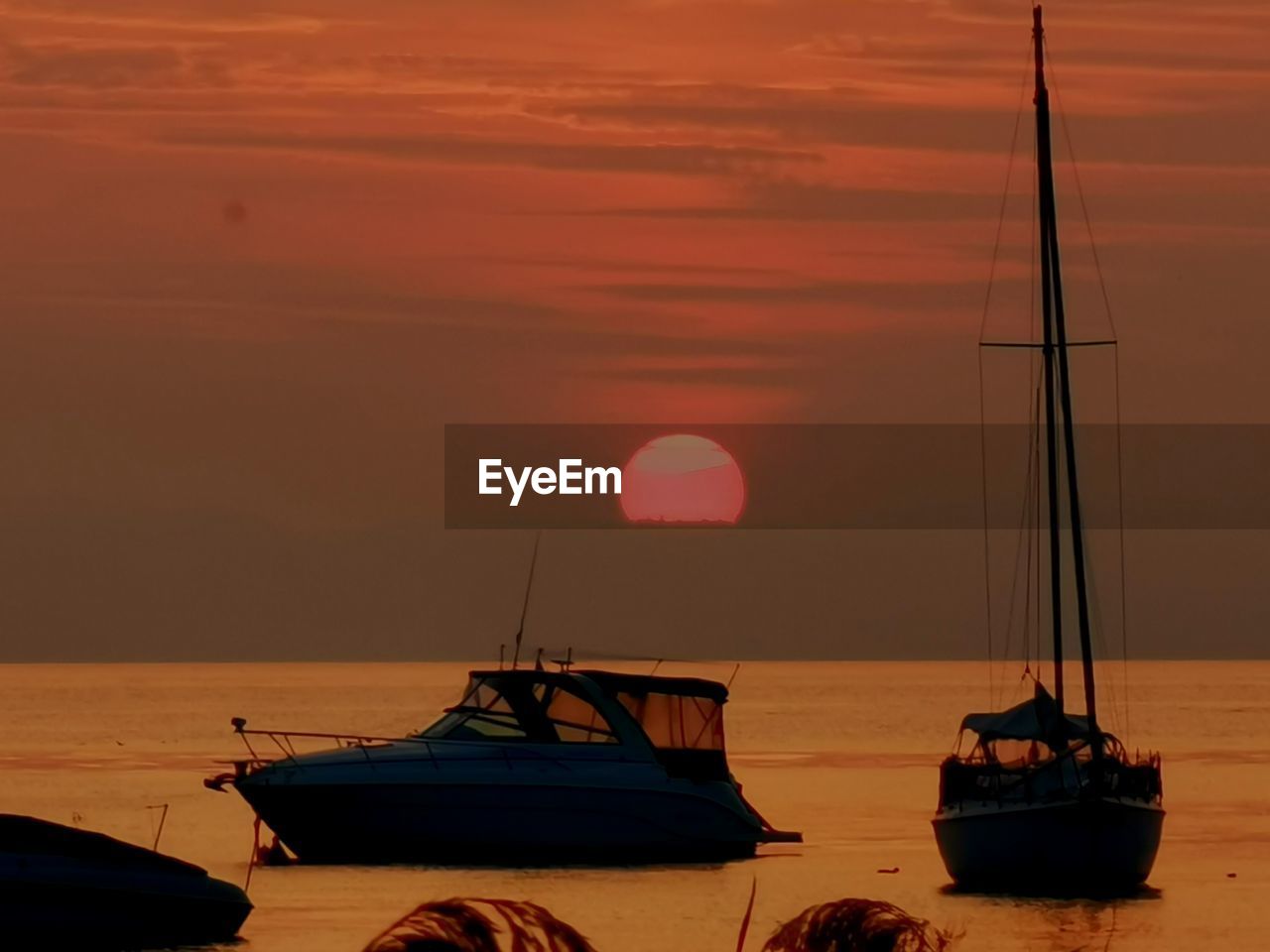 Boat moored in sea against sky during sunset