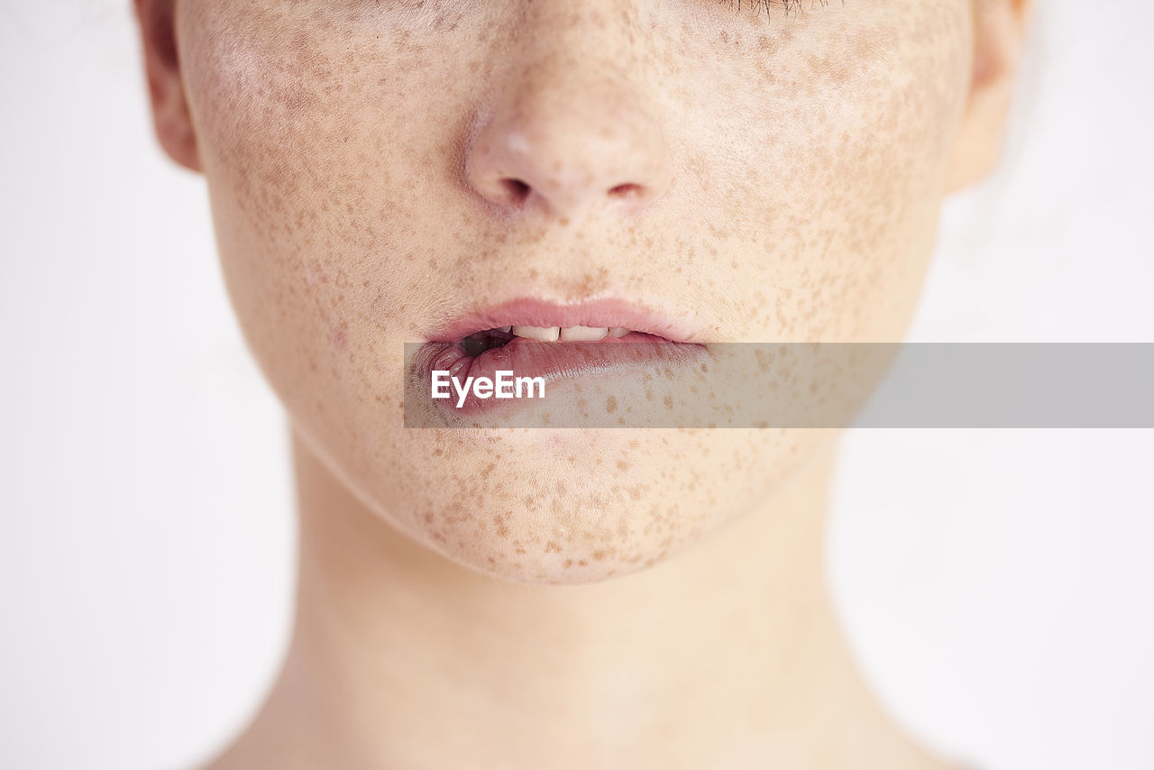 Midsection of woman with freckles on face against white background