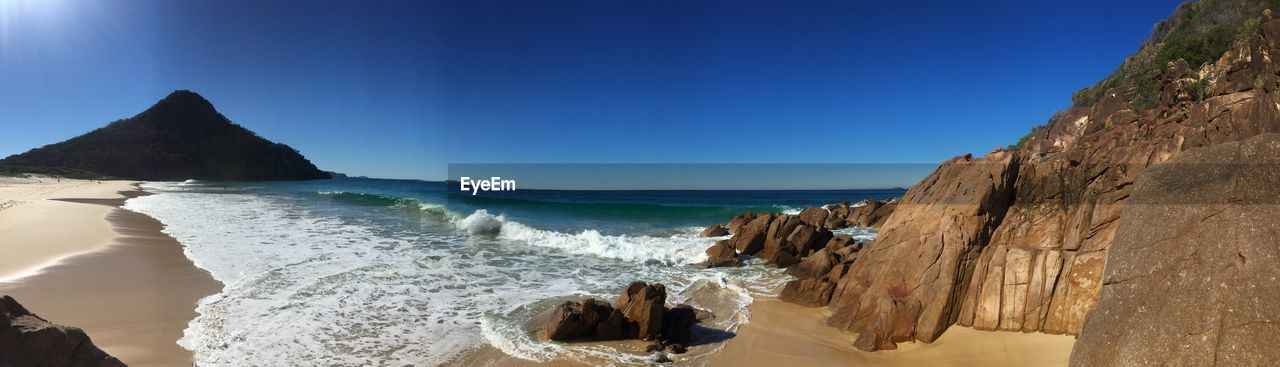 Panoramic view of beach against clear blue sky