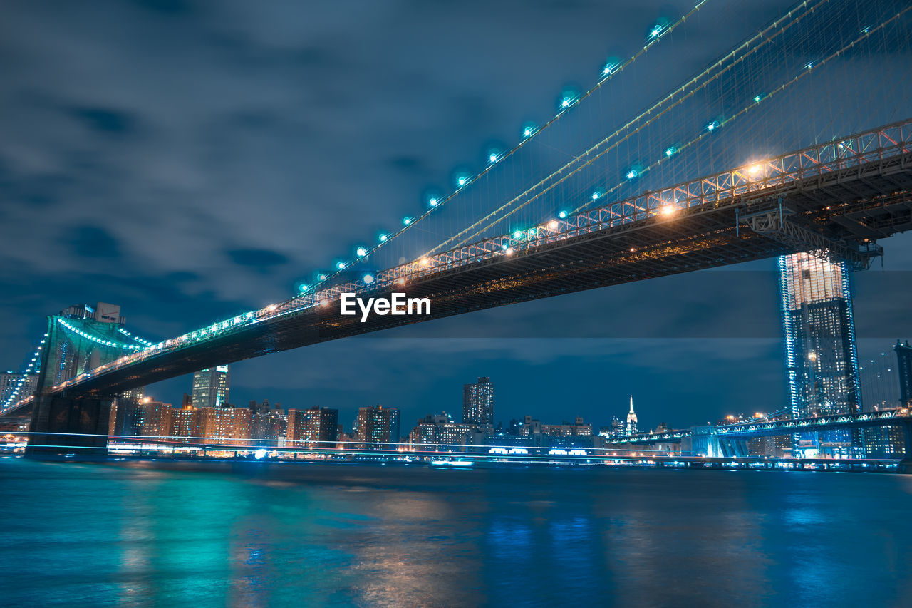 Illuminated bridge over river against sky at night