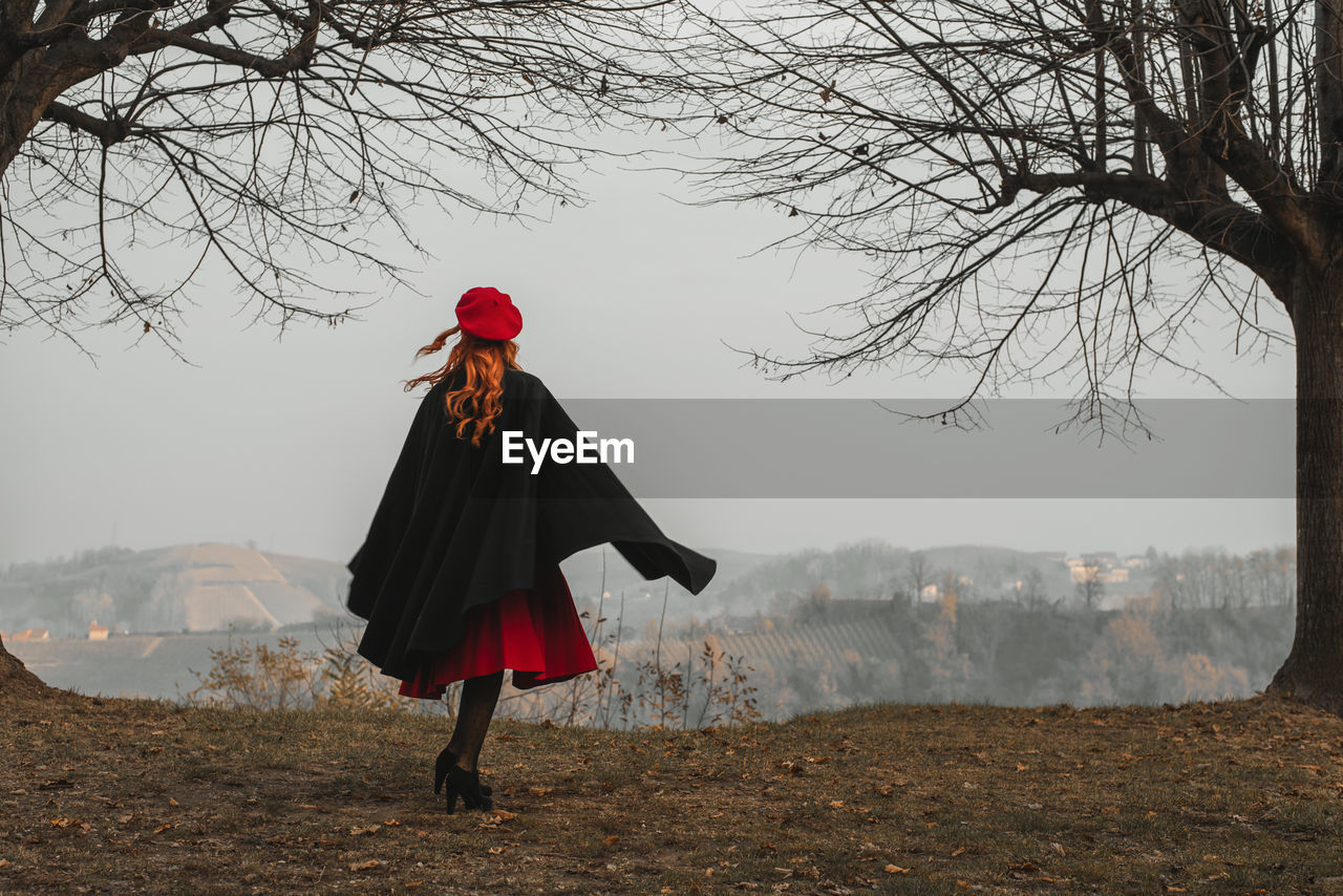 Rear view of woman standing on field against sky