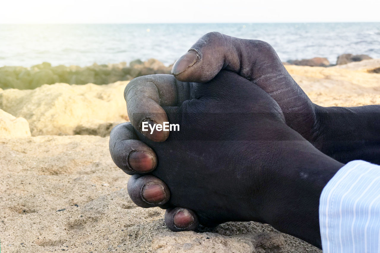 CLOSE-UP OF HAND ON ROCK AT BEACH