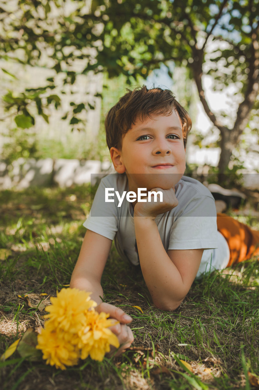 PORTRAIT OF SMILING BOY WITH YELLOW FLOWER