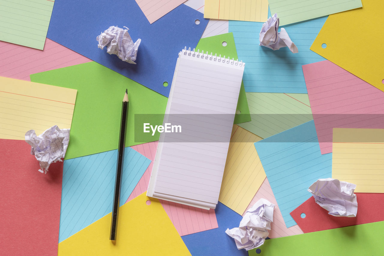 High angle view of colorful papers and pencil on table