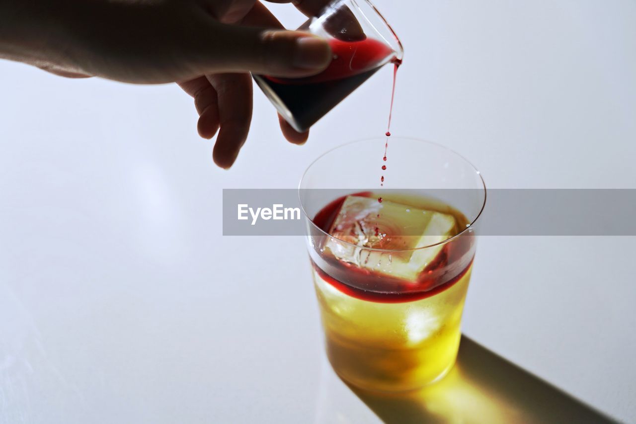 Moment of pouring red wine into drink on white background