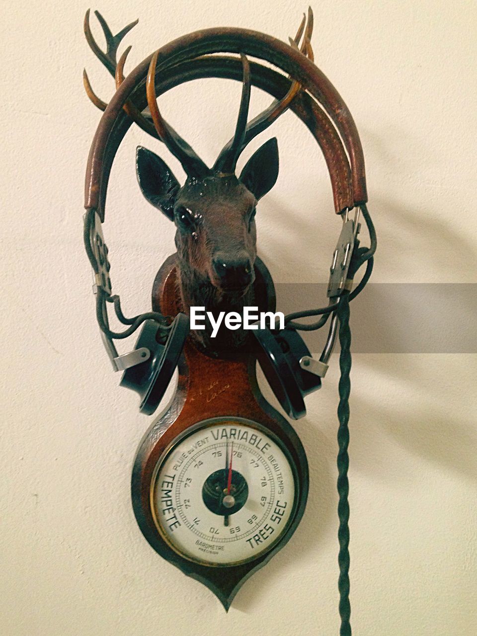 Headphones on vintage meter with deer statue against wall