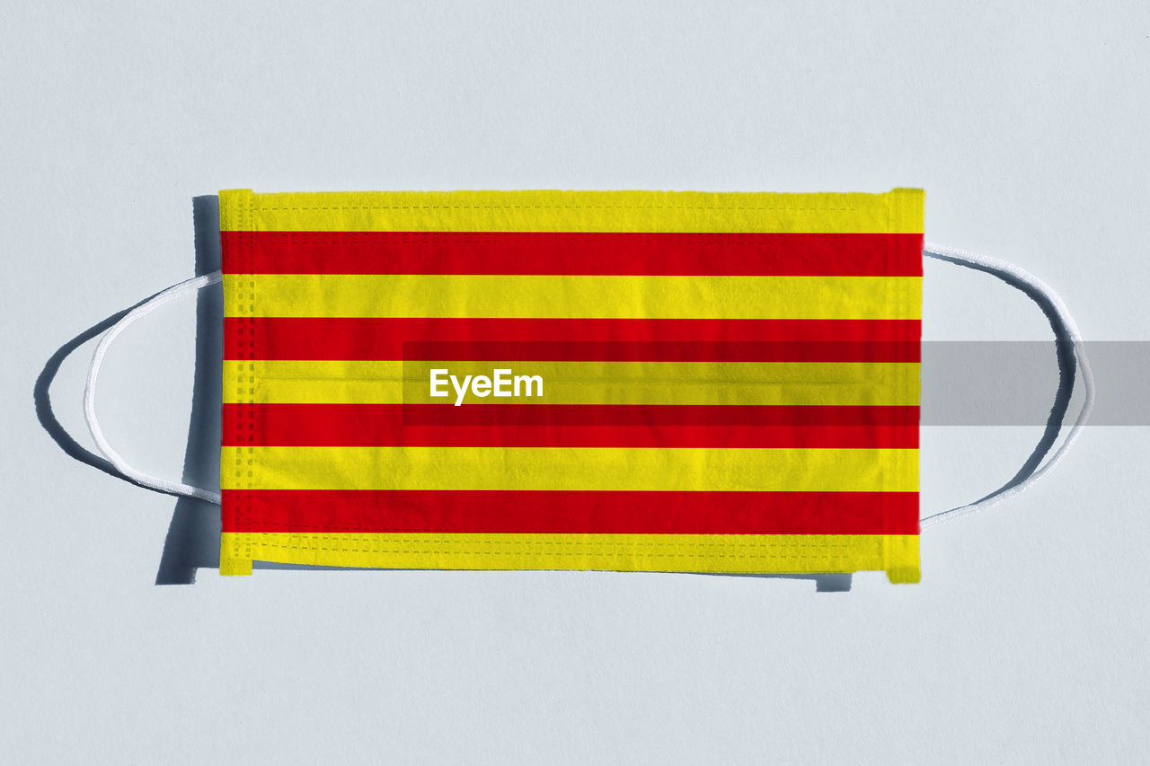 striped, flag, yellow, studio shot, multi colored, no people, indoors, patriotism, white background, red, orange, copy space, close-up, line, shape