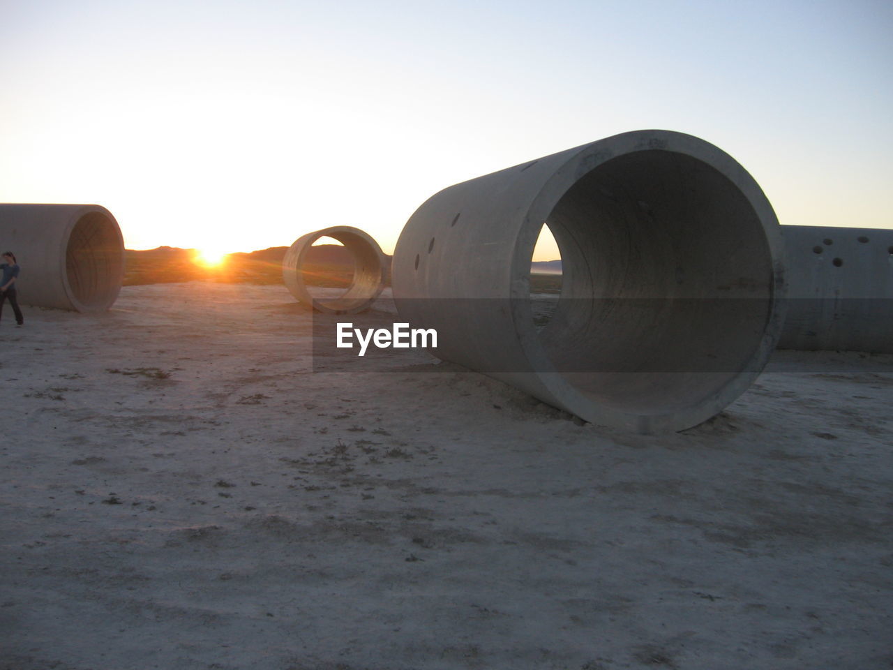 Concrete pipes on field against clear sky