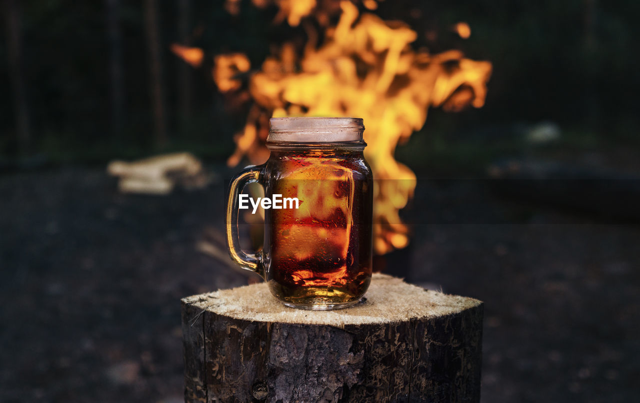 Mug of beer near roaring bonfire flames