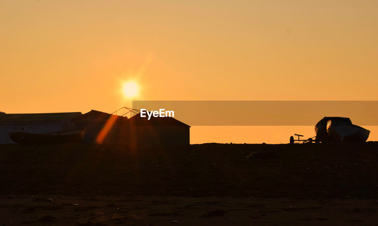 Boats moored on field against clear sky at sunrise