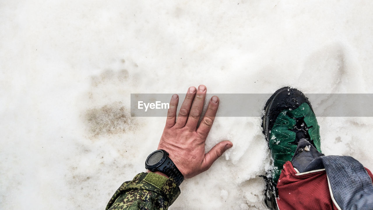 Low section of man standing on snow covered field