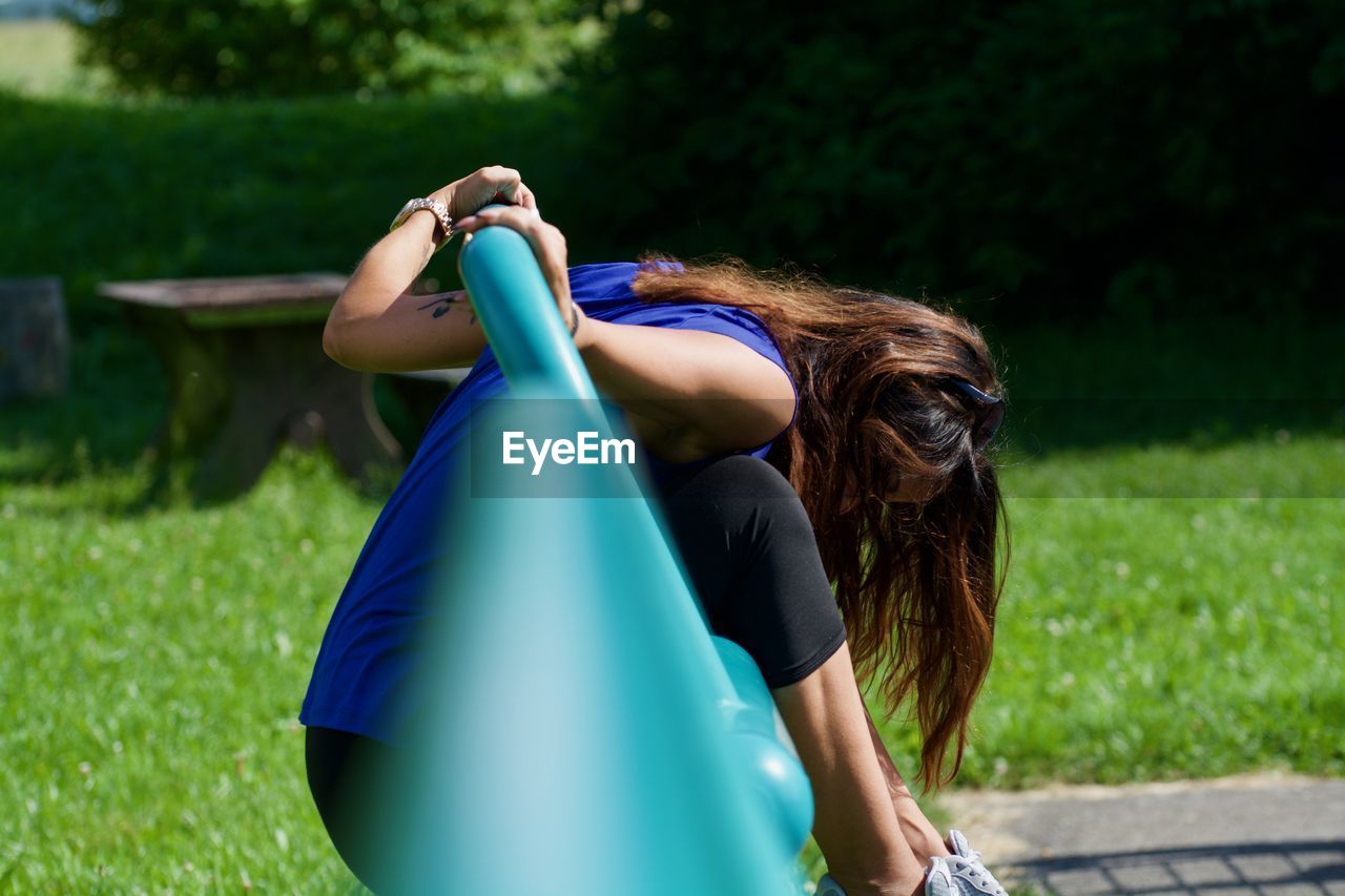 Side view of mid adult woman playing on outdoor play equipment in park