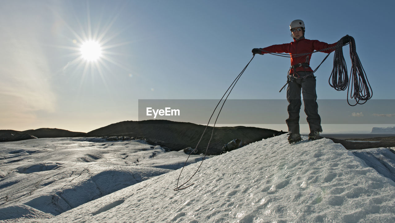 Woman taking up climbing rope on glacier in iceland