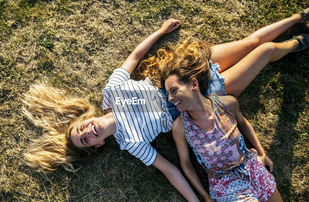 Happy young female friends relaxing on field during weekend