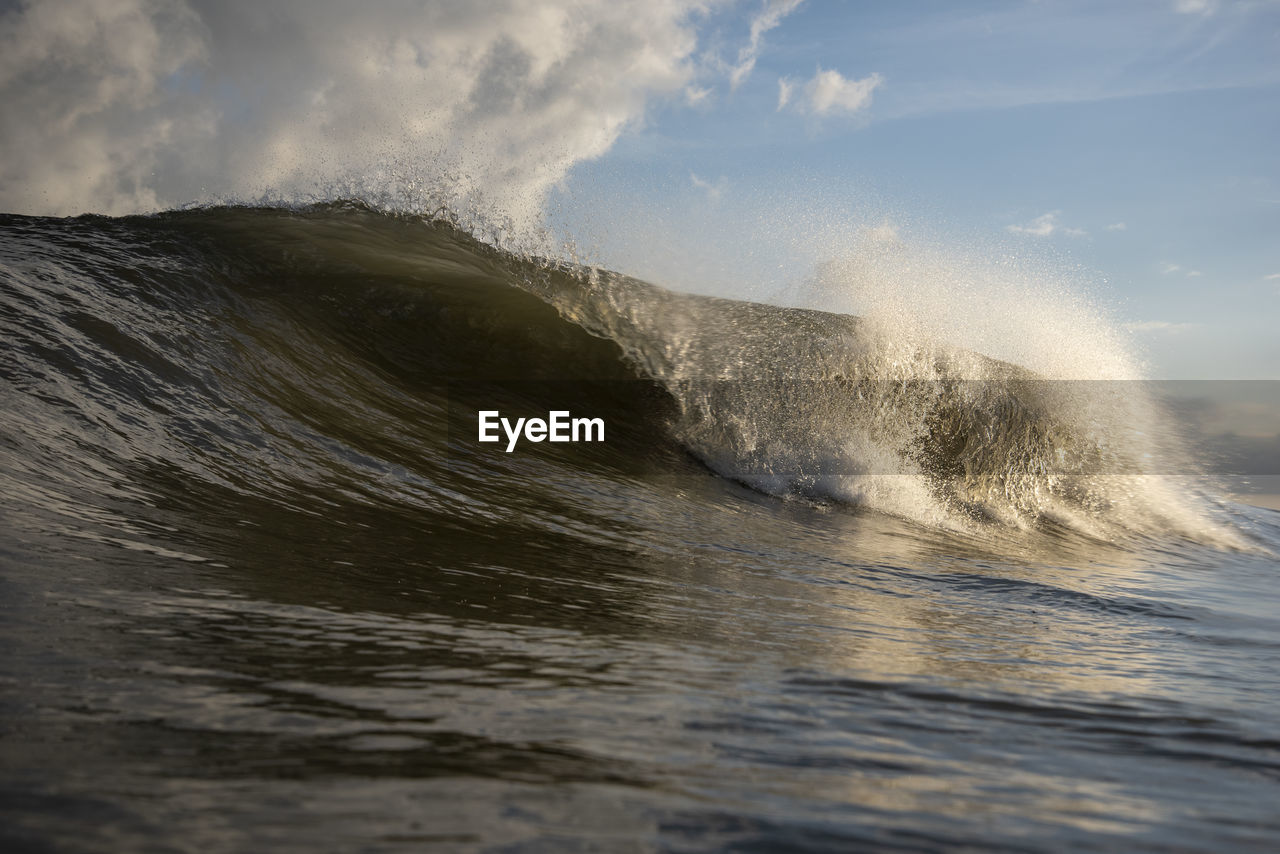 Sea waves splashing on shore against sky