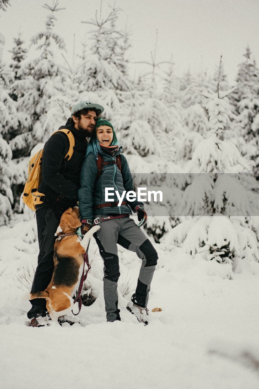 Couple in love walking on snow covered land with their dog