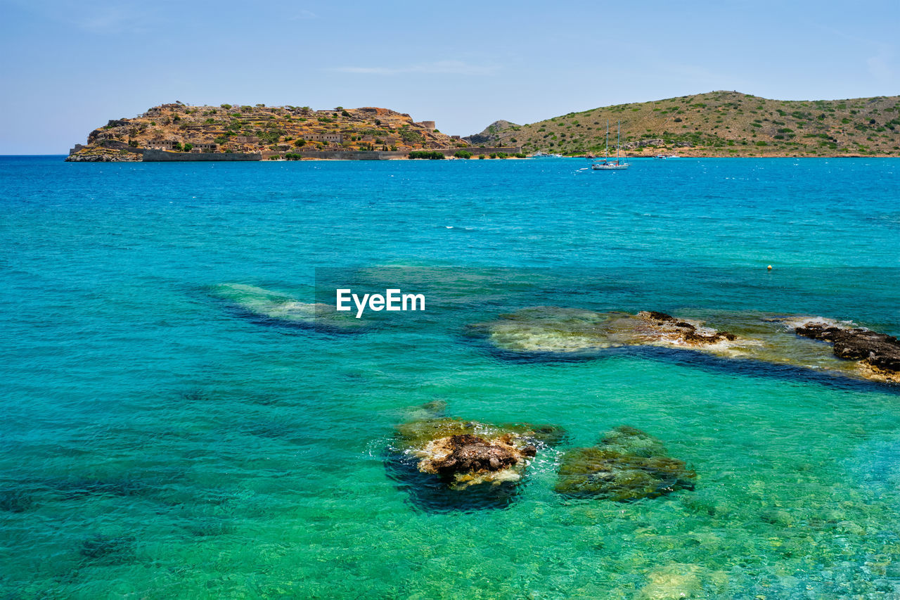 water, sea, land, scenics - nature, beauty in nature, sky, beach, islet, nature, archipelago, tranquility, blue, tranquil scene, island, travel destinations, turquoise colored, rock, ocean, idyllic, no people, travel, reef, coastline, day, environment, lagoon, holiday, outdoors, vacation, trip, tourism, tropical climate, coast, landscape, shore, body of water, seascape, clear sky, non-urban scene, cove, sea life, bay, nautical vessel, sunny, mountain, sunlight, summer, underwater, relaxation
