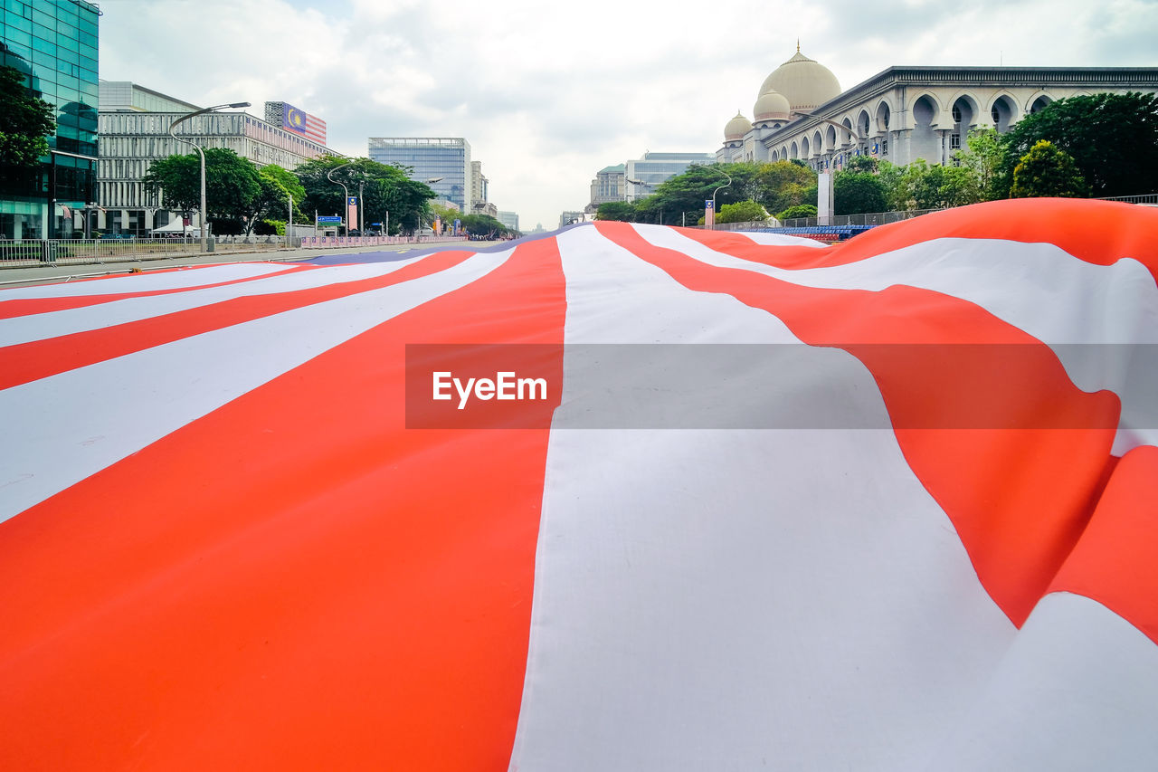 Panoramic view of red and white flag on the road against buildings