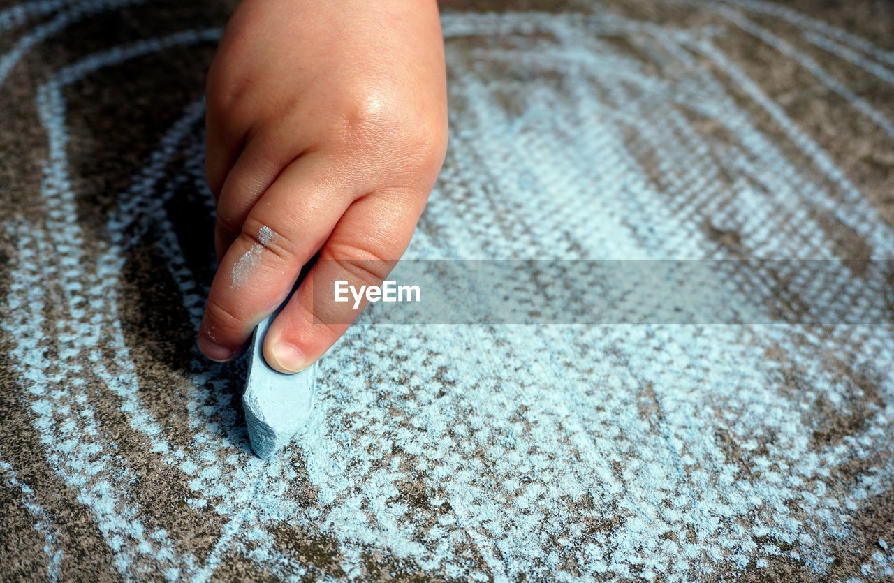 Close-up of child hand scribbling with chalk