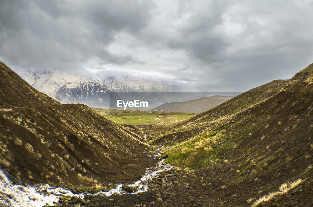 Scenic view of valley and mountains against sky