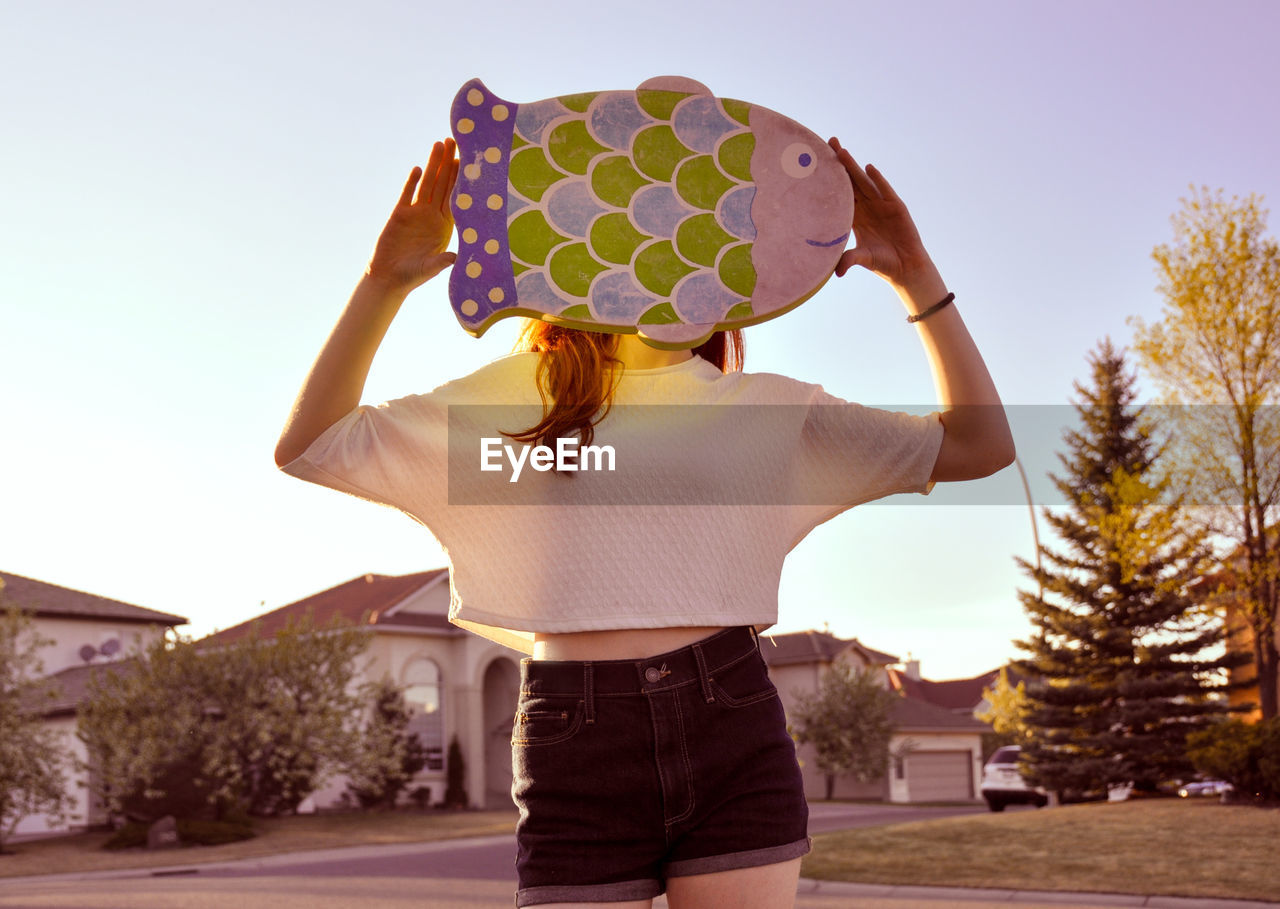 Young woman holding toy while standing against sky