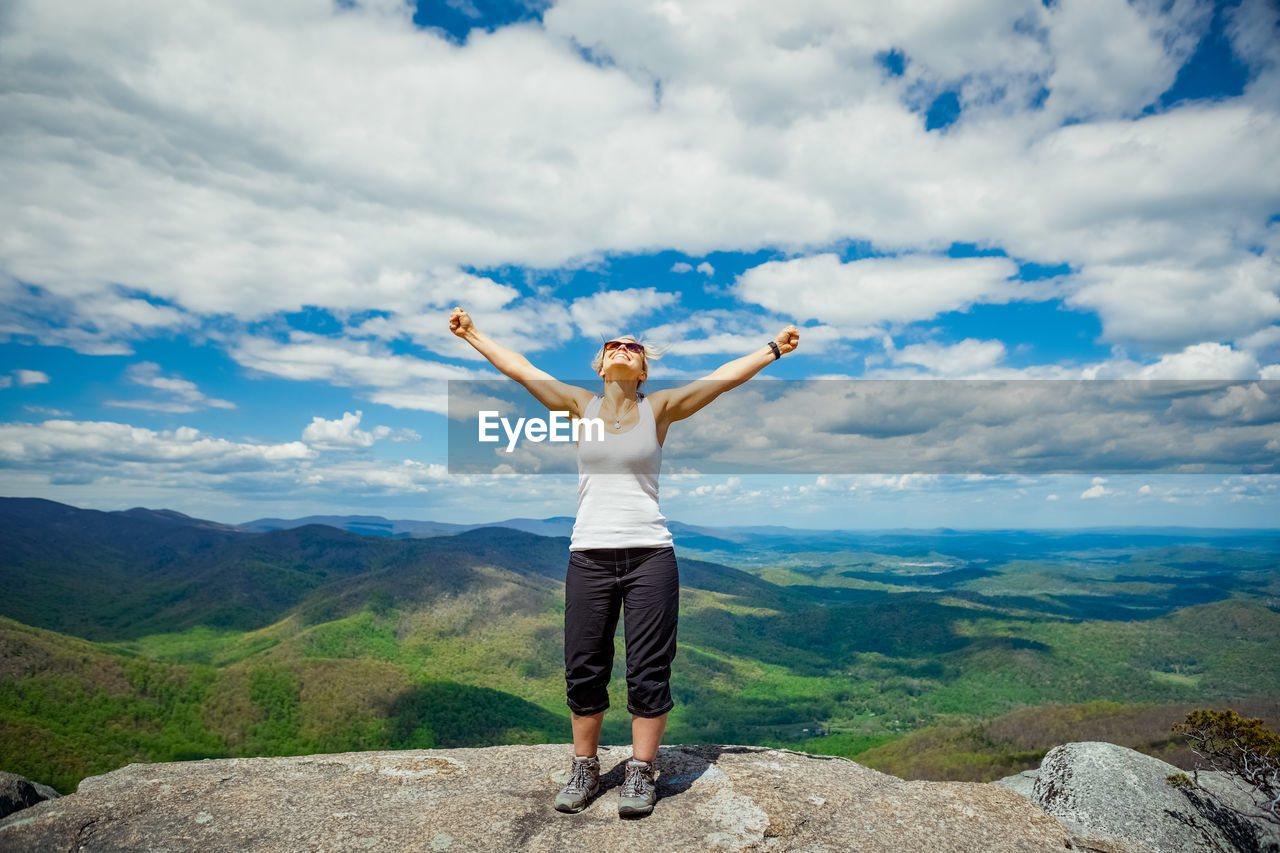 Full length of woman standing on rock against sky