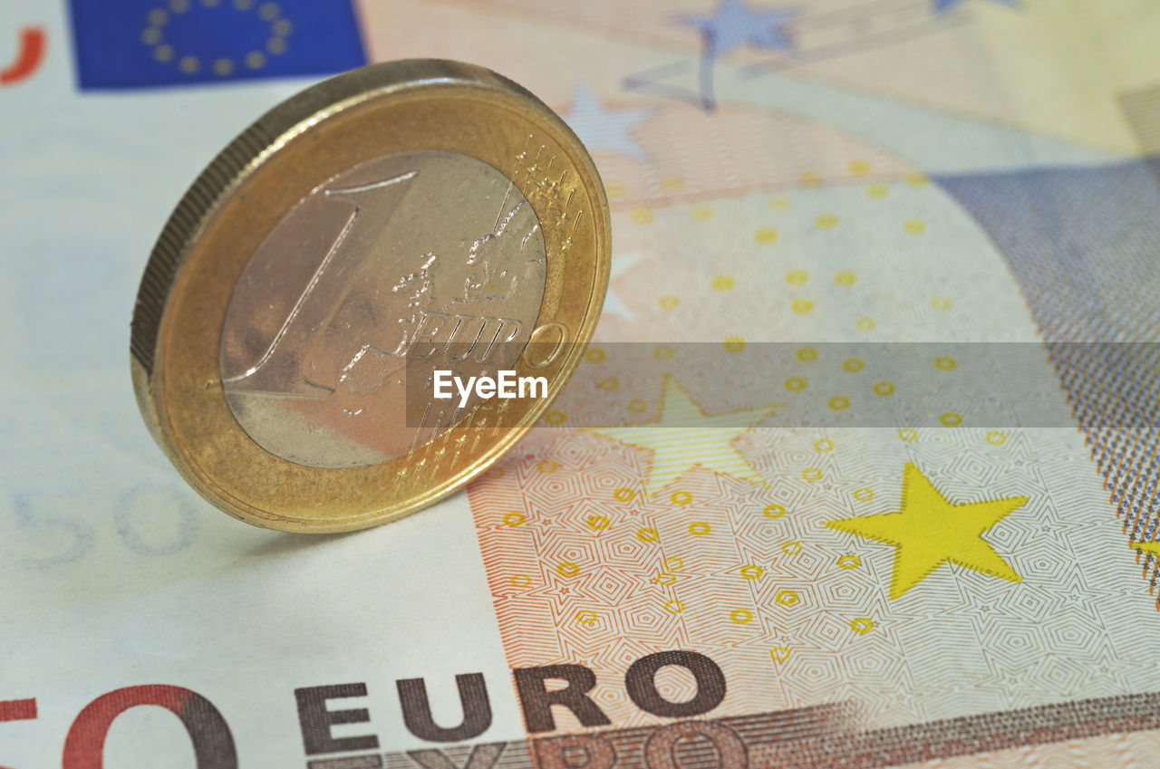 Close-up of euro coin and paper currency
