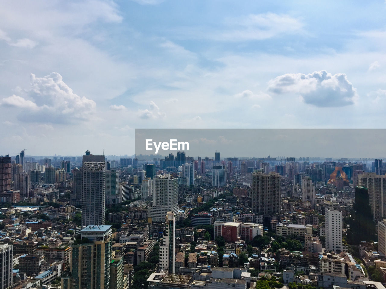 Aerial view of modern buildings in modern city against cloudy sky