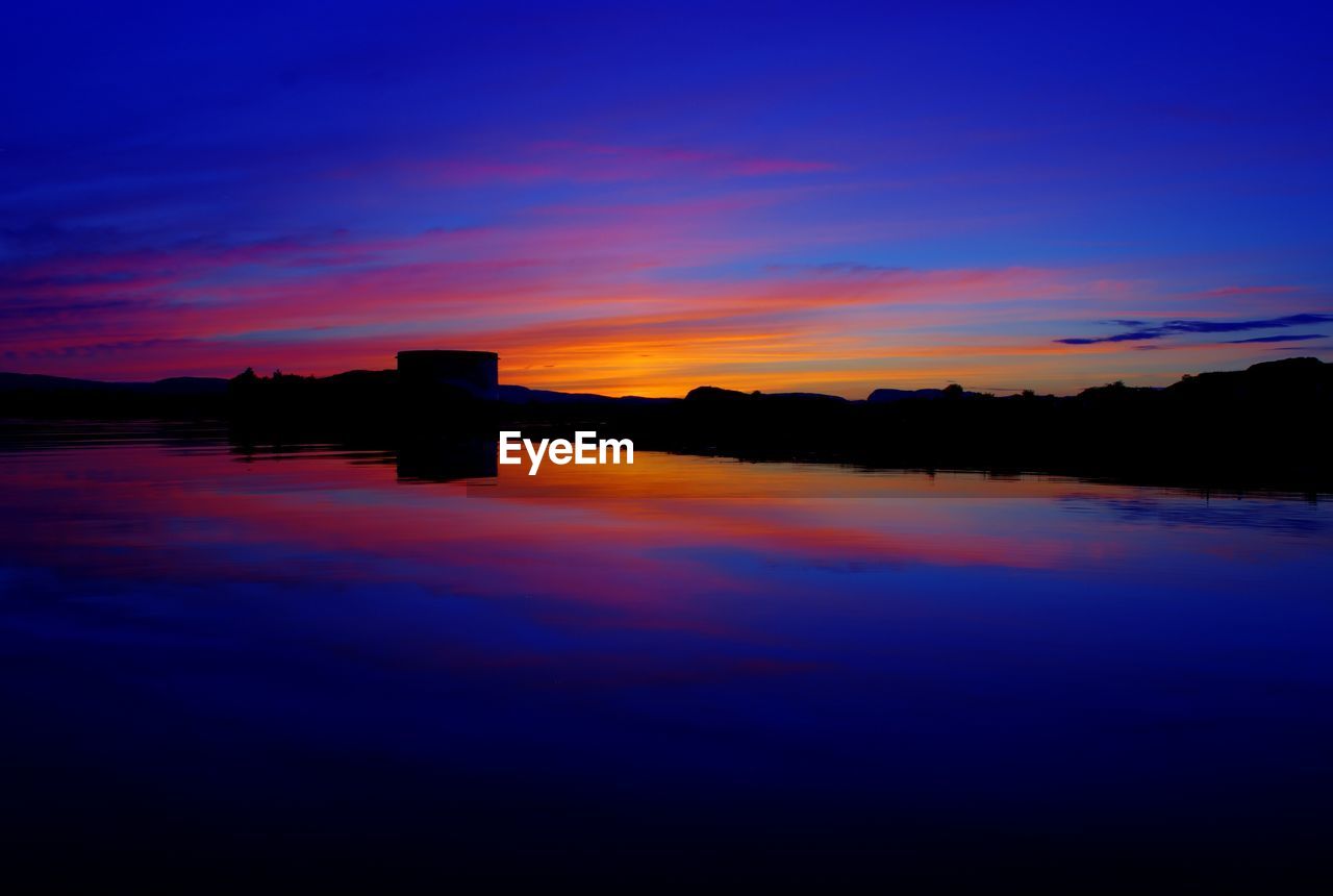 Scenic view of lake against sky at sunset