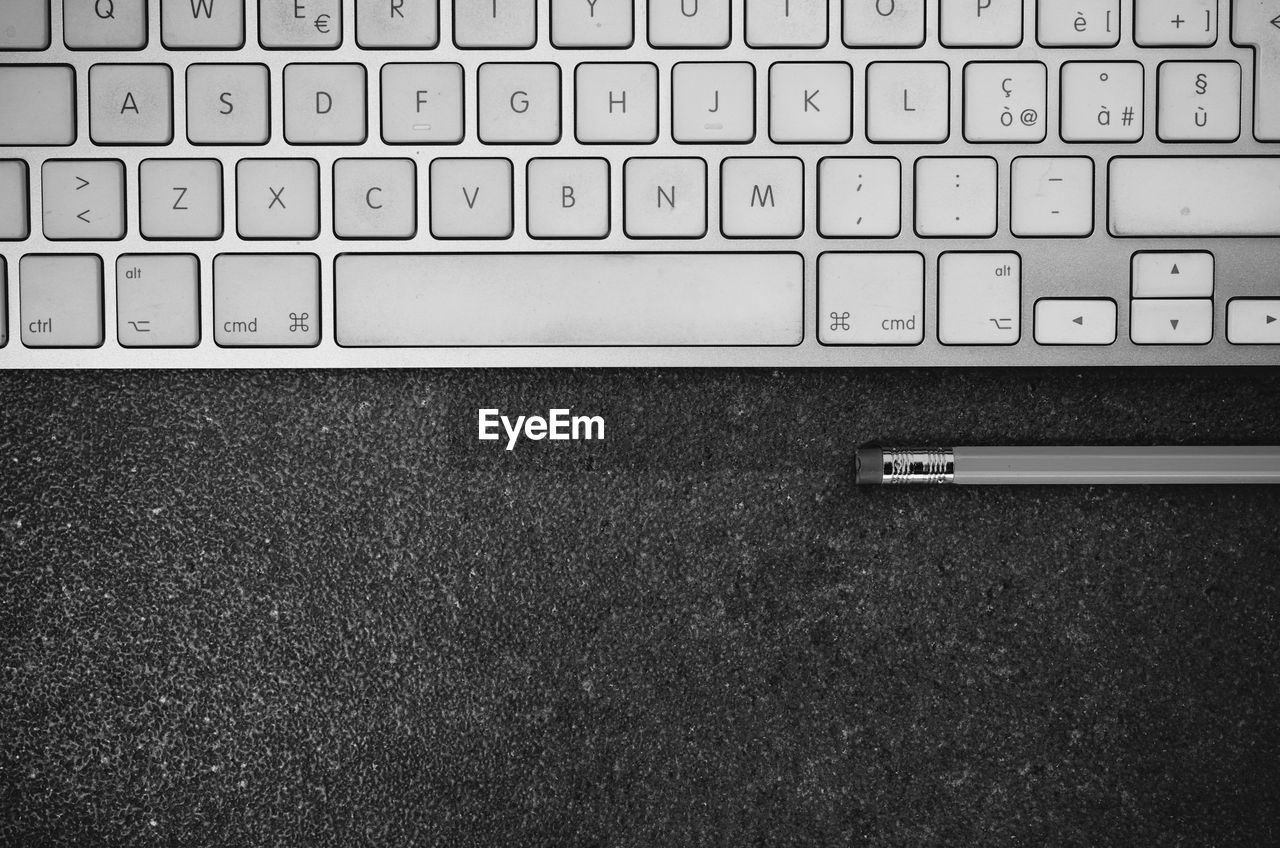 Directly above shot of computer keyboard by pencil on table