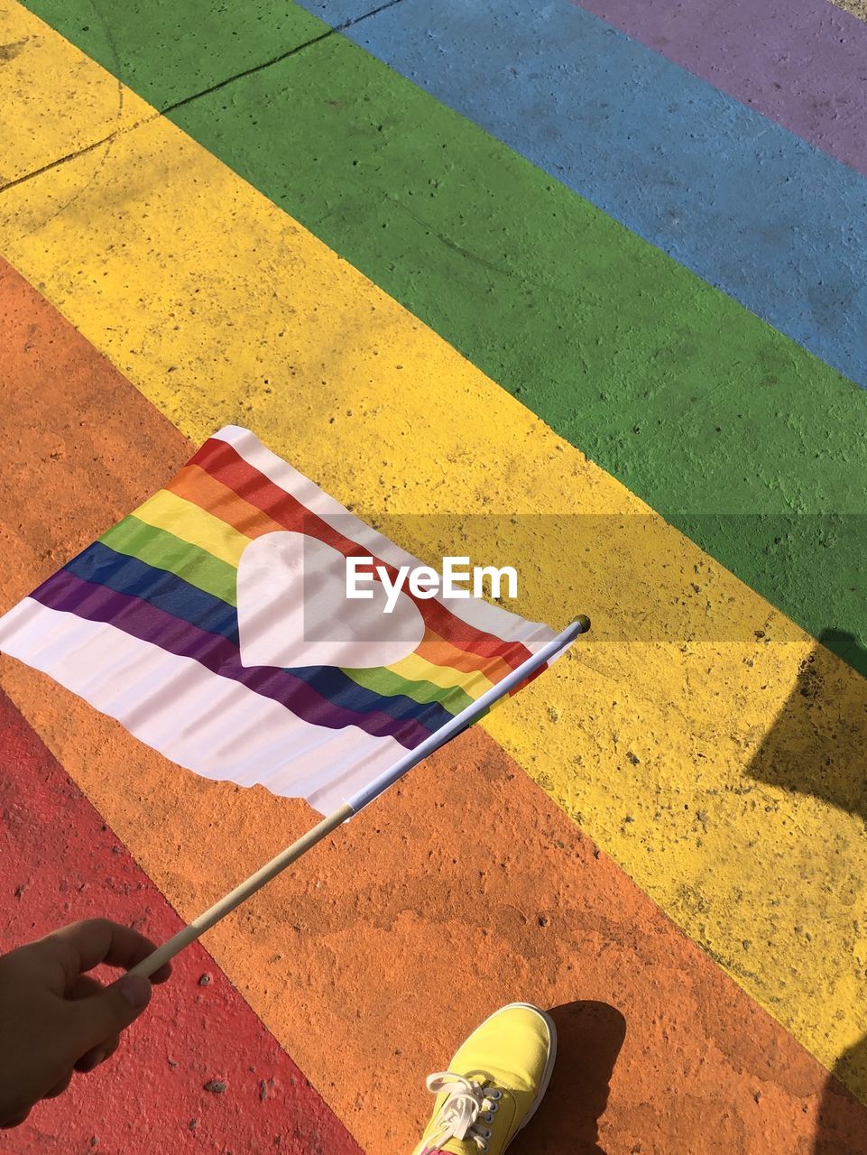 Low section of man holding rainbow flag