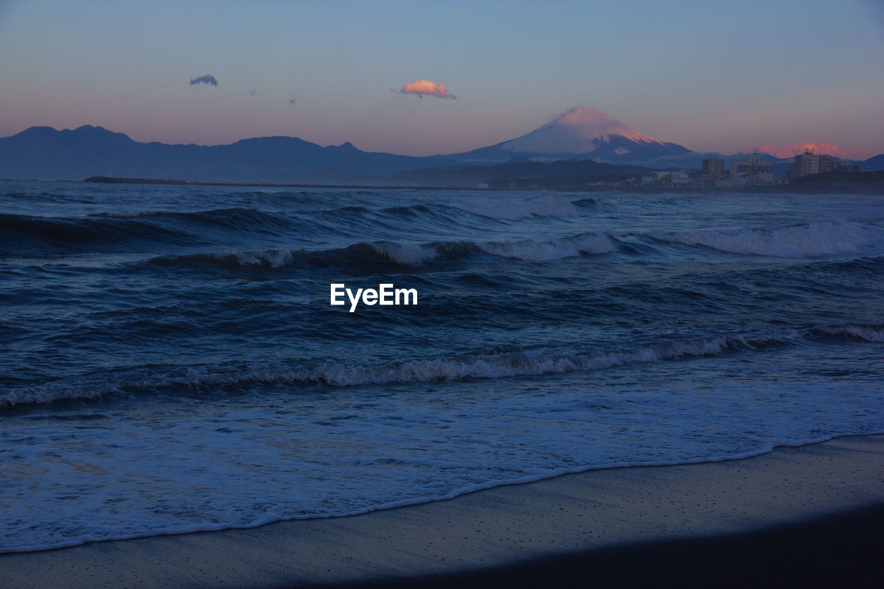 SCENIC VIEW OF BEACH AGAINST SKY AT SUNSET