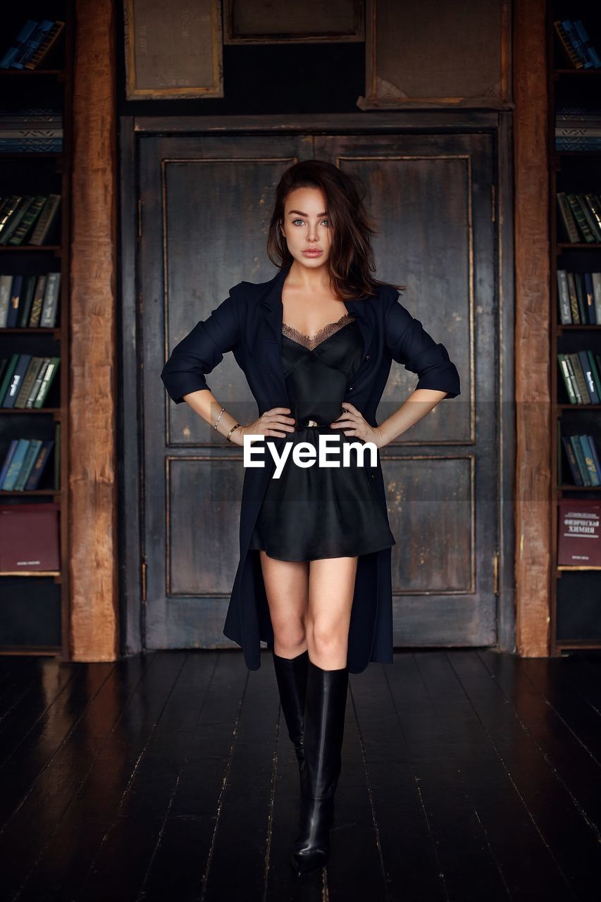 Portrait of beautiful young woman standing in old library