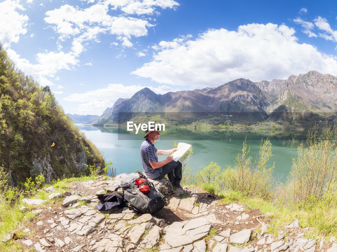 Italy, lombardy, spring at lake idro, hiker sitting with map at observation point