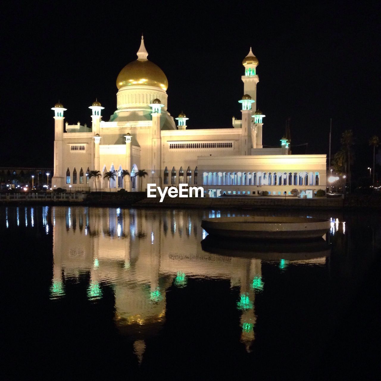 Illuminated omar ali saifuddien mosque reflected in calm river at night