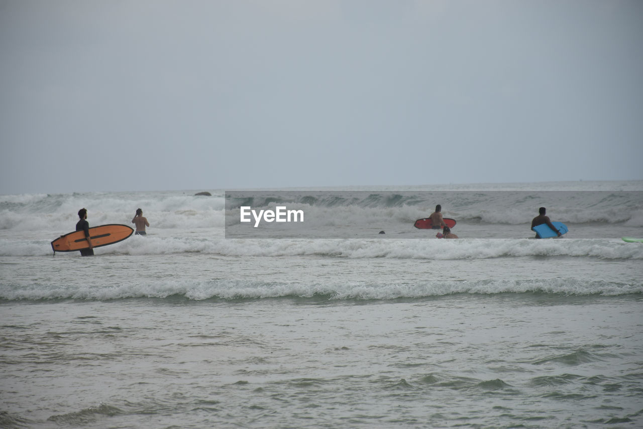 Men in sea against clear sky