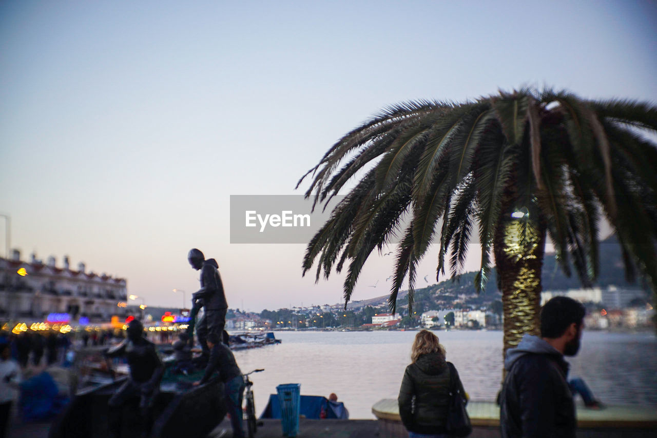 PEOPLE ON PALM TREE AGAINST SKY