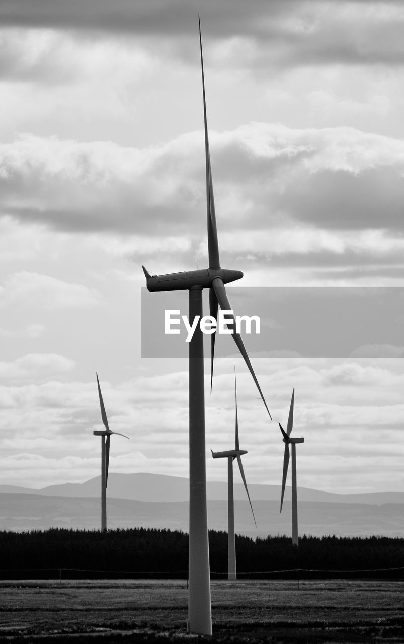 Wind turbines on field against sky